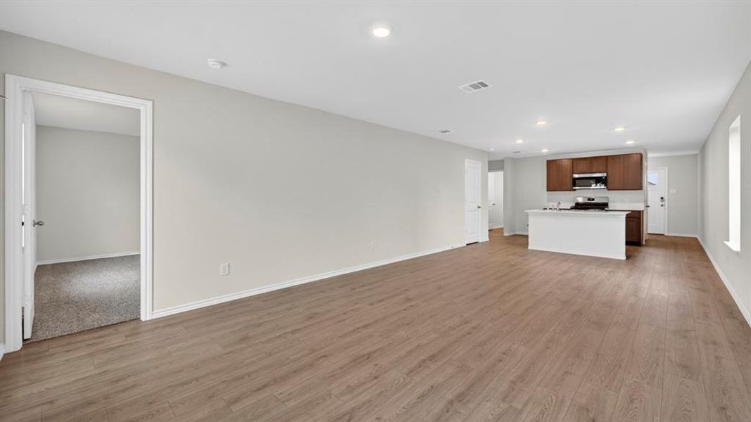 Spacious open-concept living area featuring wood-finish flooring, recessed lighting, and light-toned wall paint