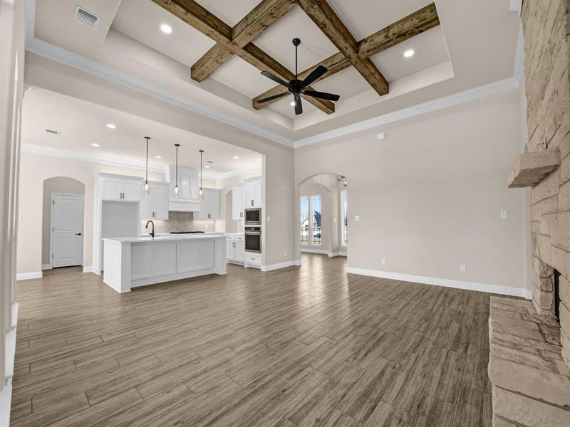 Unfurnished living room with coffered ceiling, crown molding, and beam ceiling