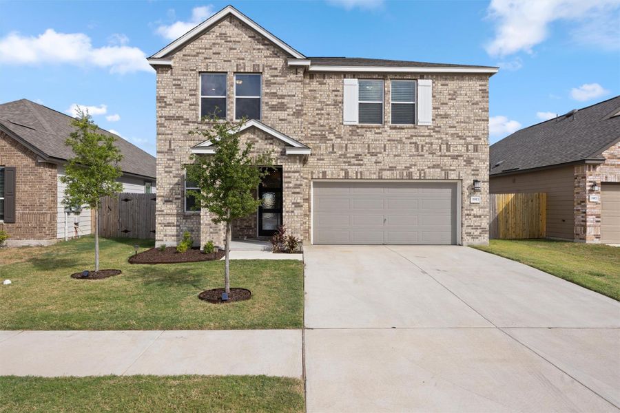 Traditional-style house featuring brick siding, concrete driveway, and an attached garage