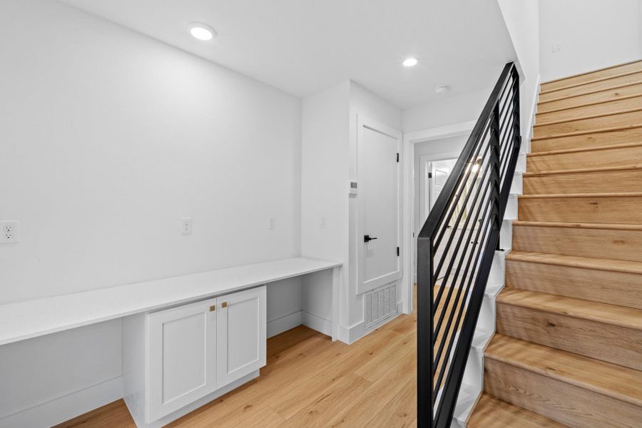 Stairway featuring built in desk, wood finished floors, and recessed lighting