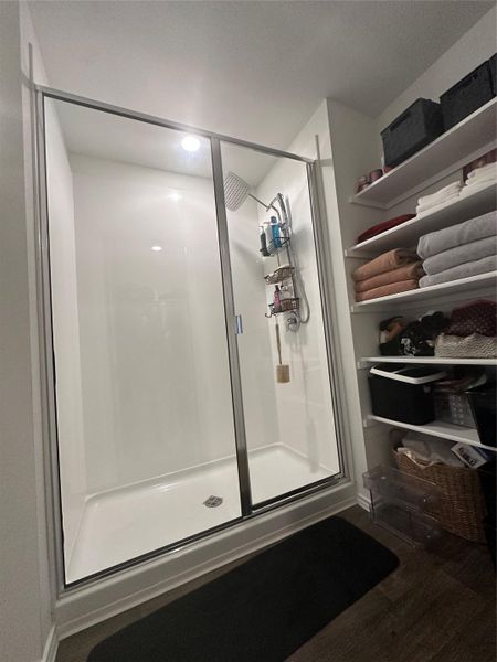 Full bath featuring a stall shower and dark wood-style flooring
