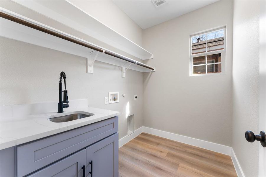 Laundry area with sink, cabinets, washer hookup, electric dryer hookup, and light wood-type flooring