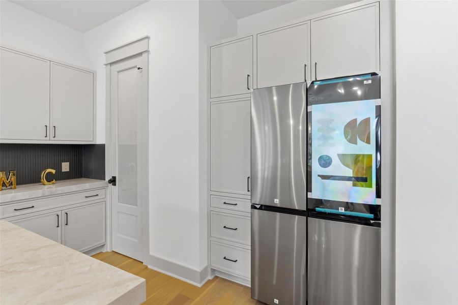 Custom inset cabinetry throughout the kitchen, a spacious walk-in pantry, and a stainless steel refrigerator included with the sale.