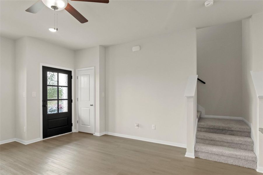 Foyer entrance featuring stairs, light wood-type flooring, and a ceiling fan Foyer entrance featuring stairs, light wood-type flooring, and a ceiling fan