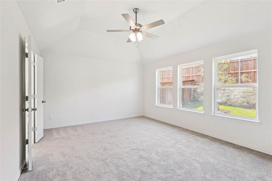 Carpeted spare room featuring ceiling fan and lofted ceiling