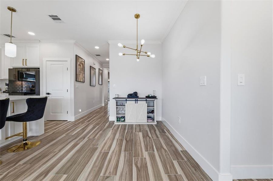 Unfurnished dining area with wood tiled floors, ornamental molding, and suspended lighting