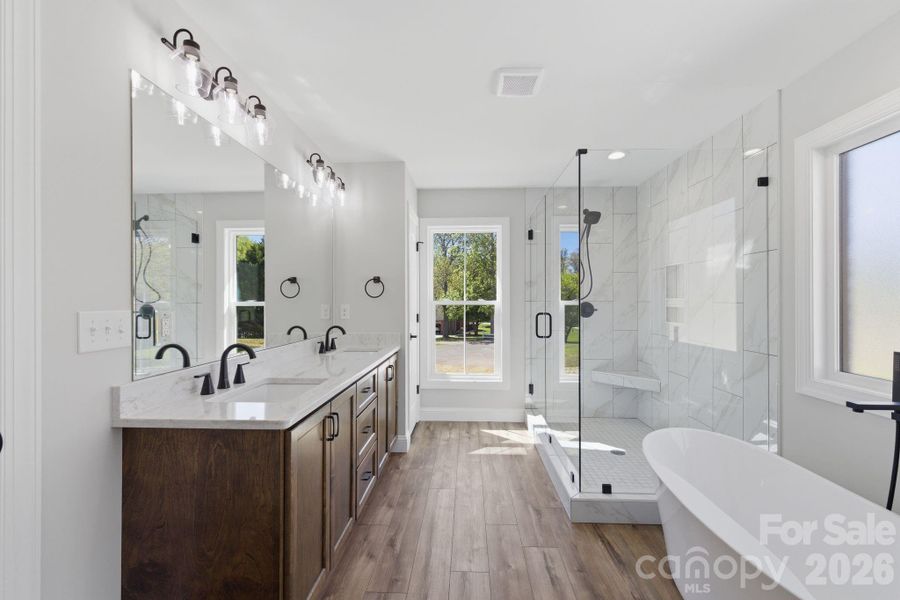 Primary bath featuring double vanities, quartz countertops, and an abundance of natural light