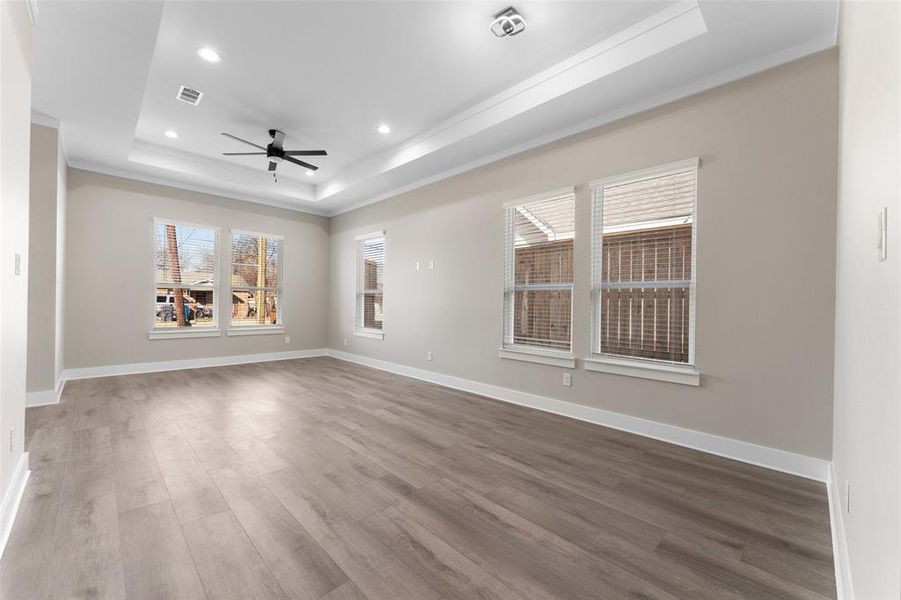 Spare room featuring crown molding, a tray ceiling, wood-type flooring, and ceiling fan