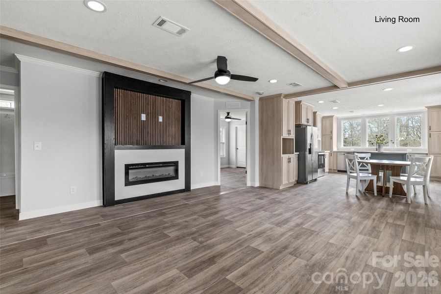 Living room with beamed ceiling and electric fireplace.