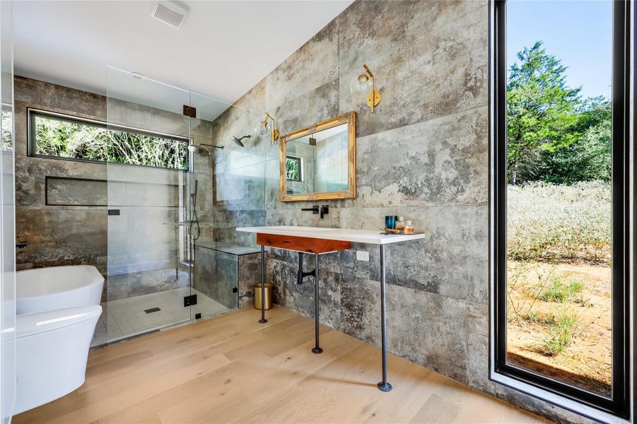 Full bathroom with a shower stall, wood finished floors, and tile walls