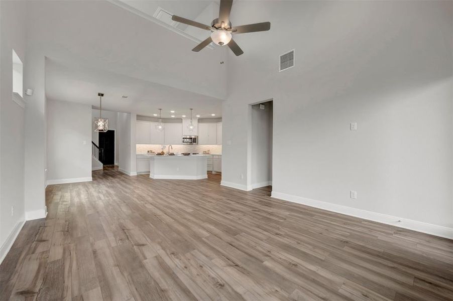 Spacious living area featuring high vaulted ceilings, wood-finish flooring, a contemporary ceiling fan, and recessed lighting