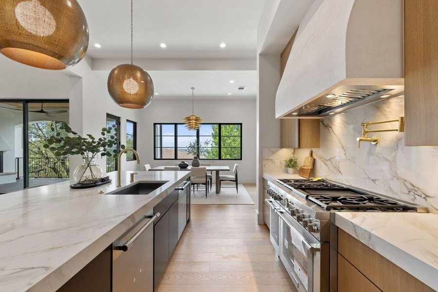 Contemporary kitchen featuring an expansive island with an undermount sink, integrated dishwasher, and pendant lighting