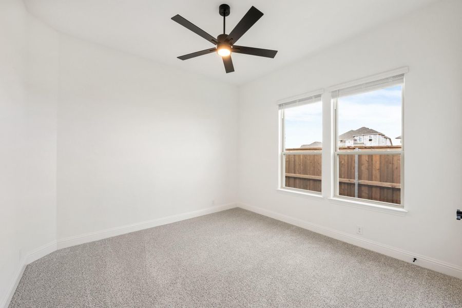 Empty bedroom with gray carpet, white walls, ceiling fan, and double window