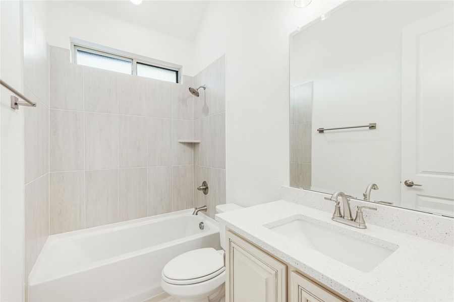Bathroom with tiled tub and shower combo, white quartz vanity, and large mirror