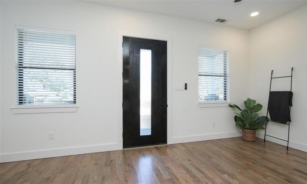 View toward the modern front door from the kitchen showcasing the abundant natural light.