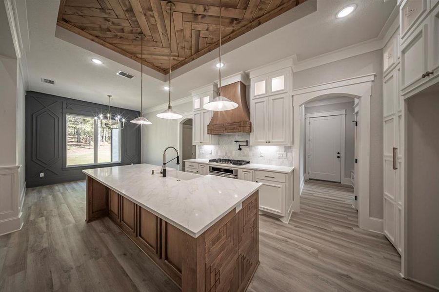 Kitchen with arched walkways, a center island with sink, white cabinets, glass insert cabinets, and recessed lighting Kitchen with arched walkways, a center island with sink, white cabinets, glass insert cabinets, and recessed lighting