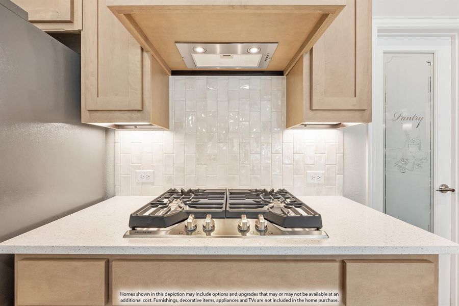 Kitchen cooktop area with stainless gas range, white tile backsplash, light wood cabinets, and built-in range hood Kitchen cooktop area with stainless gas range, white tile backsplash, light wood cabinets, and built-in range hood