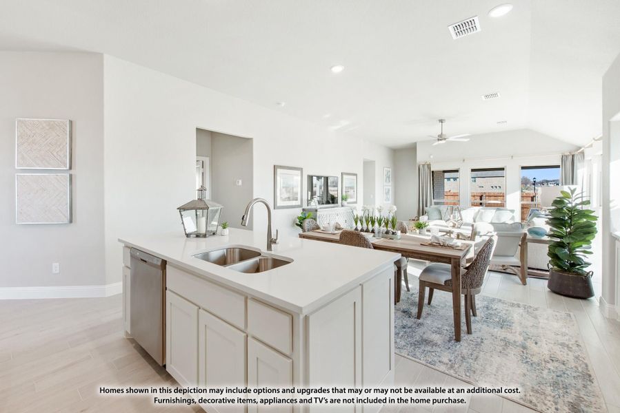 Open-concept kitchen with white island and sink flowing into dining and living areas with vaulted ceiling Open-concept kitchen with white island and sink flowing into dining and living areas with vaulted ceiling