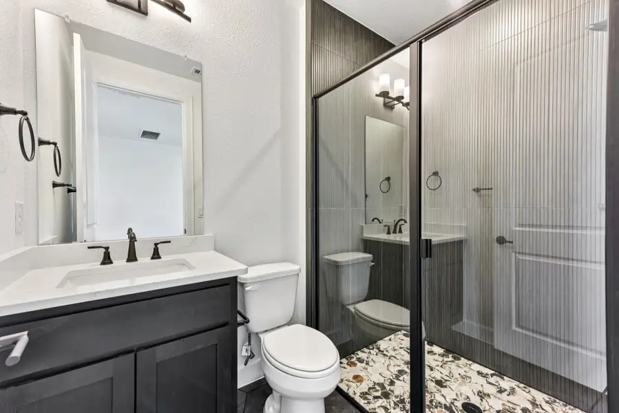 Full bath with vanity, a textured wall, and a stall shower