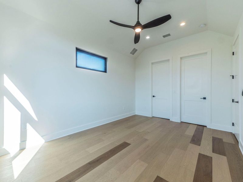 Unfurnished bedroom featuring lofted ceiling, light wood finished floors, ceiling fan, recessed lighting, and two closets Unfurnished bedroom featuring lofted ceiling, light wood finished floors, ceiling fan, recessed lighting, and two closets