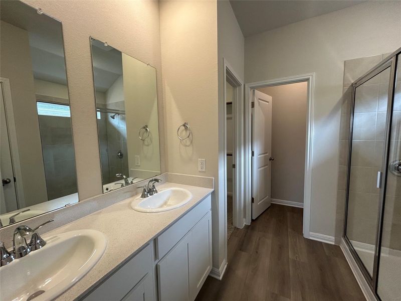 Bathroom with a shower stall, wood finished floors, and double vanity Bathroom with a shower stall, wood finished floors, and double vanity