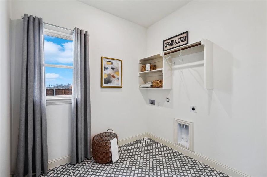 Laundry room featuring patterned tile flooring, built-in shelving, hanging rod, and a window for natural light