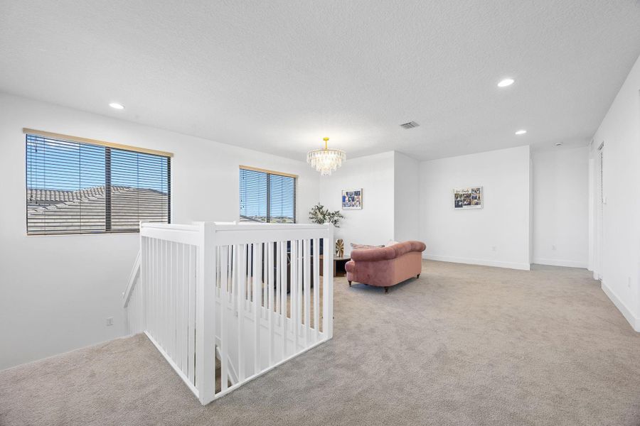 Hallway with recessed lighting, light carpet, an upstairs landing, and a chandelier