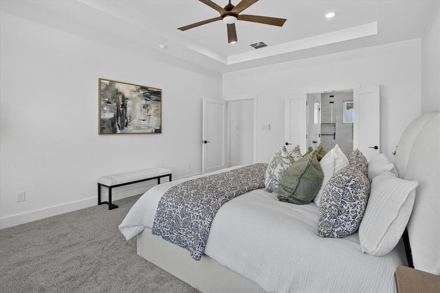 Carpeted room featuring a ceiling fan with integrated lighting, tray ceiling, and white double doors
