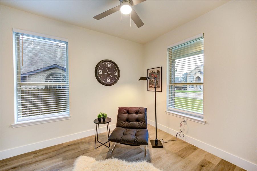 A cozy, well-lit Den with two large windows,   the hardwood floor and light walls create a warm, inviting atmosphere.