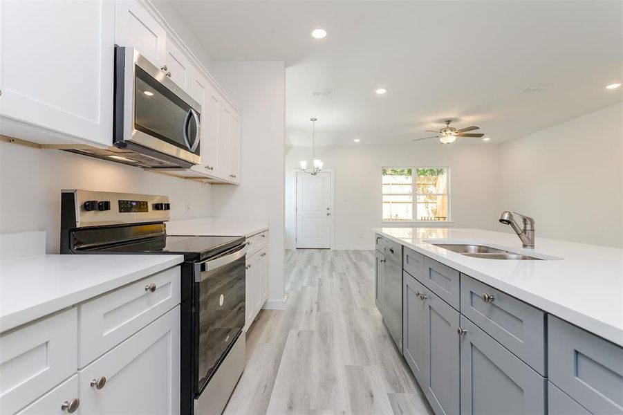 Kitchen featuring light hardwood / wood-style flooring, stainless steel appliances, white cabinets, sink, and ceiling fan