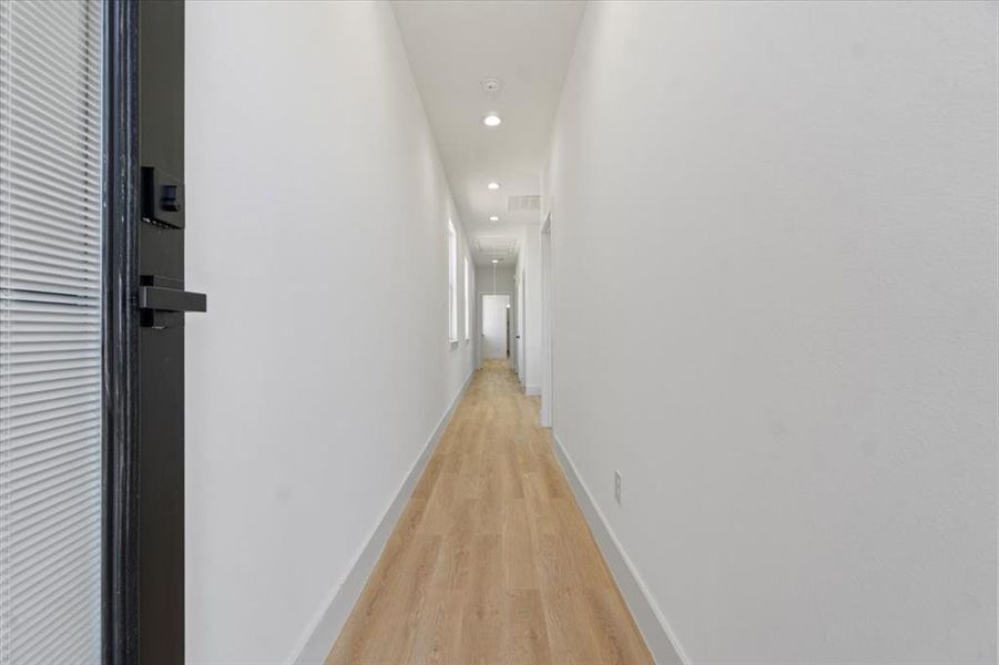 Corridor with recessed lighting, visible vents, attic access, light wood-style floors, and baseboards