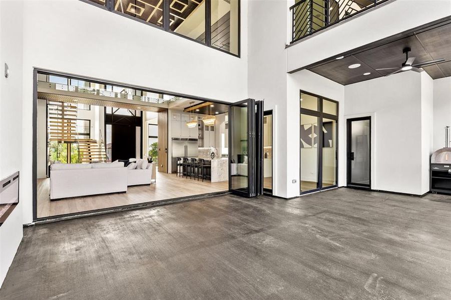 Expansive living area featuring bi-fold glass doors, high ceilings, and polished concrete flooring