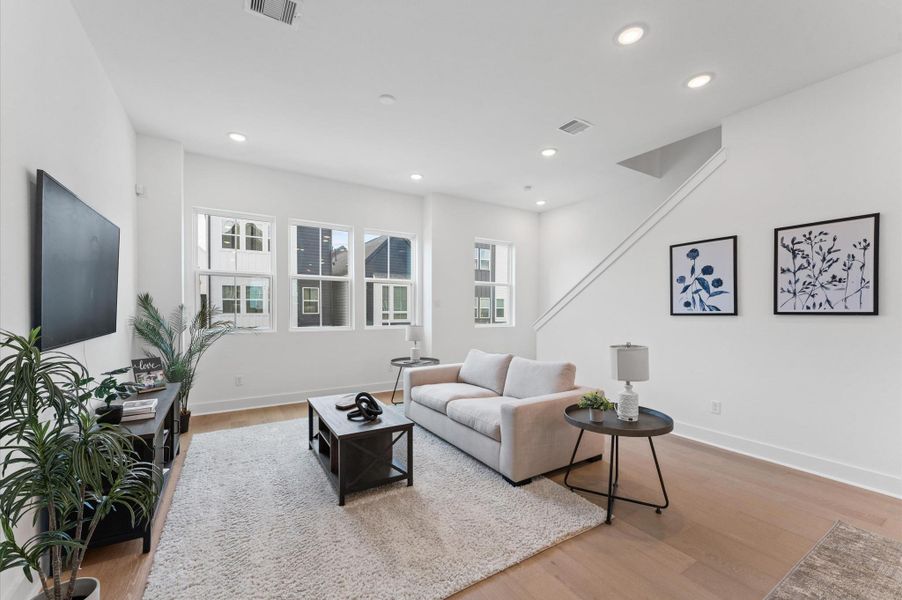 Flooded with natural light, this expansive living area features a wall of oversized windows that frame picturesque views of the lush community courtyard.