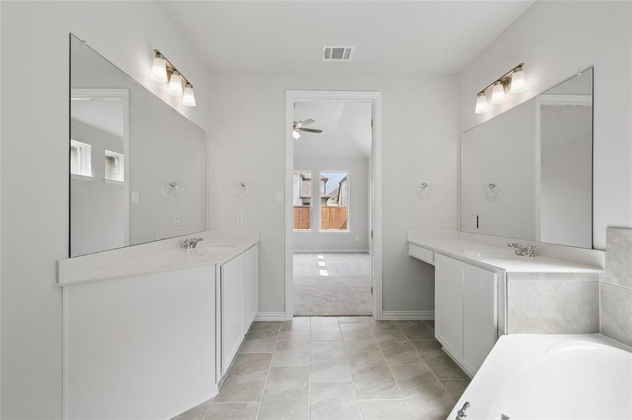 Full bathroom with two vanities, light tile patterned floors, a garden tub, and light colored carpet