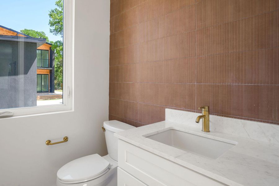 Bathroom featuring toilet, vanity, and tile walls