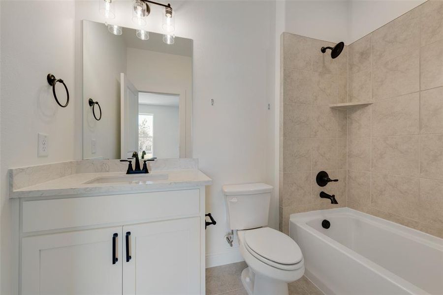 Full bathroom featuring tile patterned flooring, toilet, vanity, and tiled shower / bath