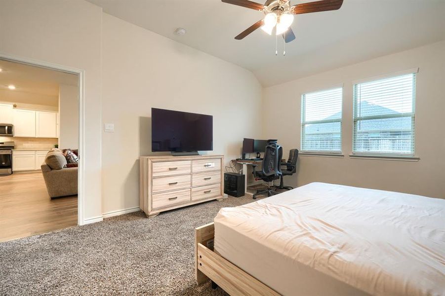Bedroom with light colored carpet, vaulted ceiling, and a ceiling fan Bedroom with light colored carpet, vaulted ceiling, and a ceiling fan