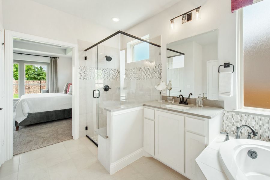 Master ensuite bathroom with glass walk-in shower, double vanity, soaking tub, and view into bedroom Master ensuite bathroom with glass walk-in shower, double vanity, soaking tub, and view into bedroom