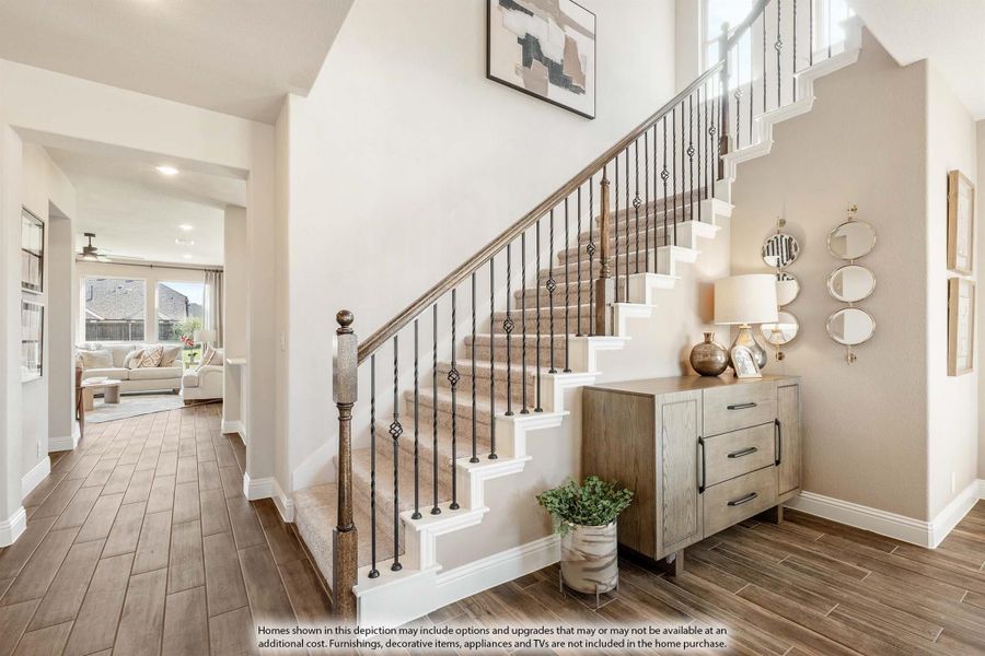 Entryway with carpeted staircase, iron balusters, wood-look tile floors, and view into living room Entryway with carpeted staircase, iron balusters, wood-look tile floors, and view into living room
