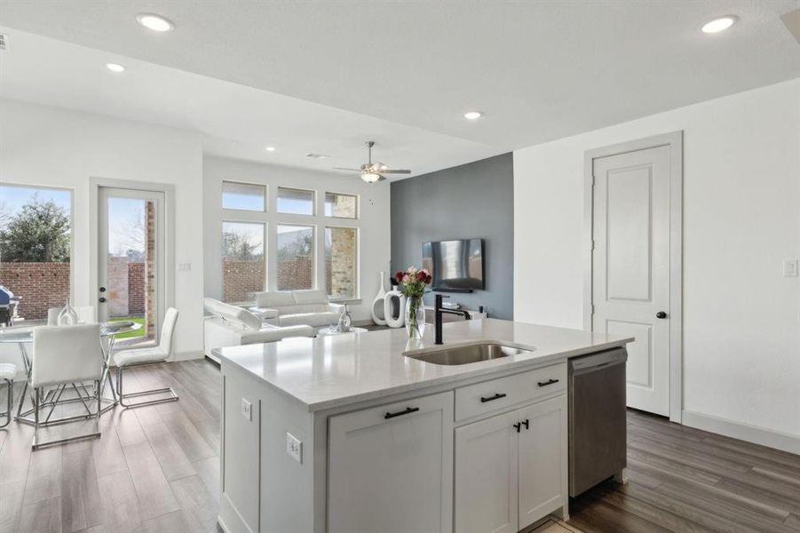 Kitchen with white cabinets, recessed lighting, light stone counters, open floor plan, and dark wood-style flooring Kitchen with white cabinets, recessed lighting, light stone counters, open floor plan, and dark wood-style flooring