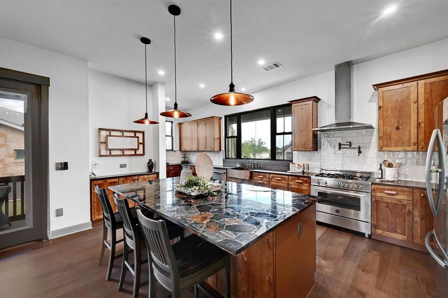 Kitchen featuring a breakfast bar area, dark wood finished floors, appliances with stainless steel finishes, a kitchen island, and recessed lighting