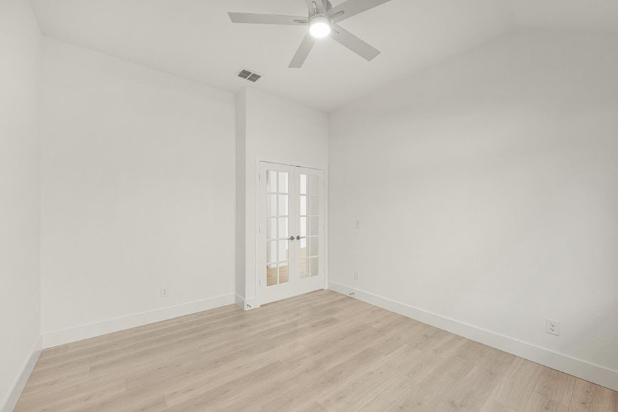 Empty room with light wood floors, white walls, ceiling fan, and French doors