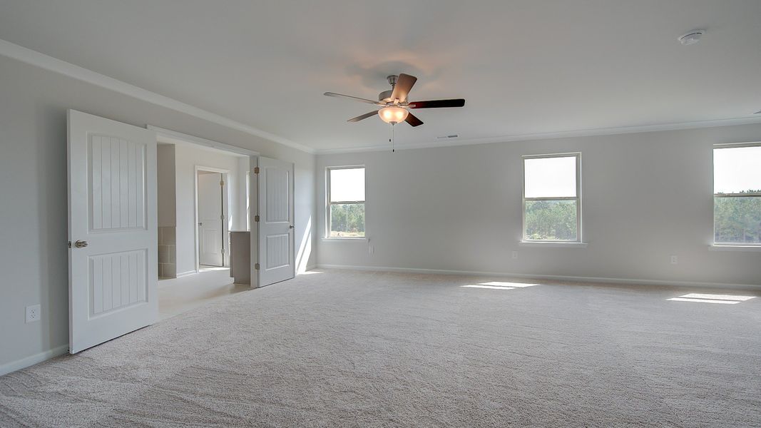McKinley II expansive primary suite with carpet flooring, natural light, and sitting area at Brighton in Locust Grove, GA.