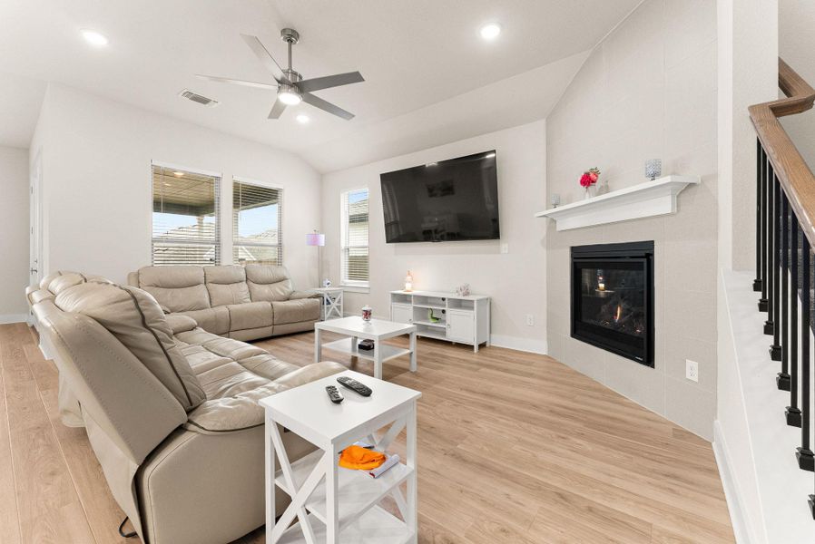 The spacious family room features a corner gas fireplace with mantle, ceiling fan with light, recessed lighting, and two-inch blinds.