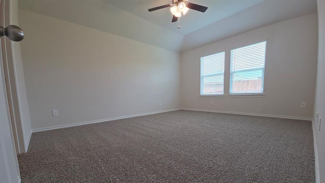 Spacious room featuring neutral carpeting, light-toned walls, and a tray ceiling