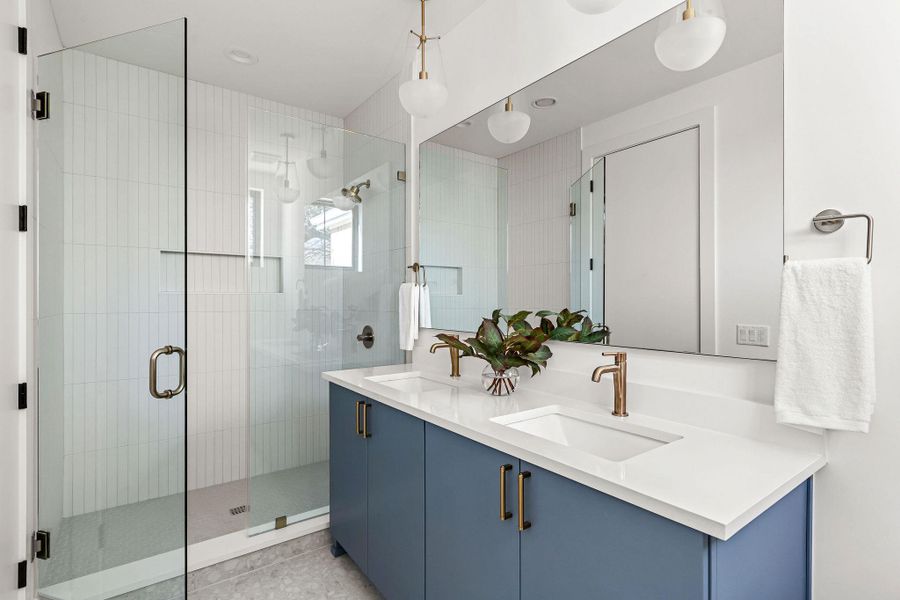 Full bath with a stall shower, double vanity, and light tile patterned flooring