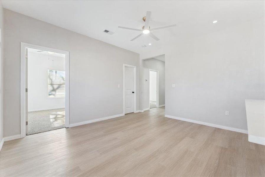 Spare room with light wood-type flooring, baseboards, visible vents, and a ceiling fan