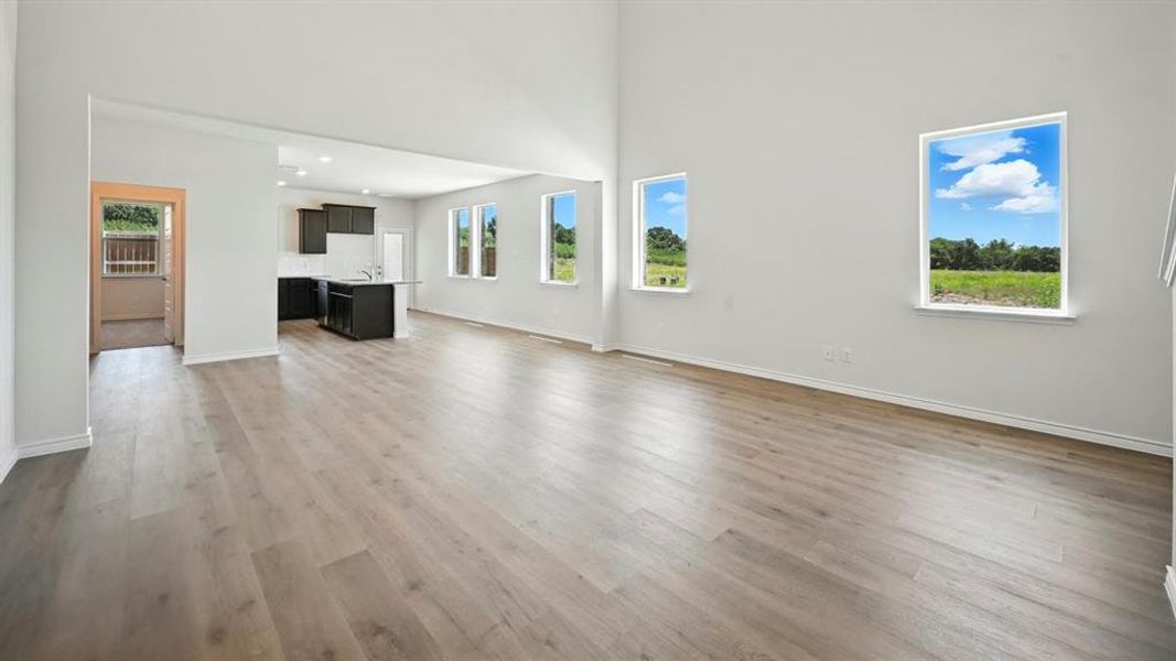 Unfurnished living room with plenty of natural light, a high ceiling, and light wood finished floors