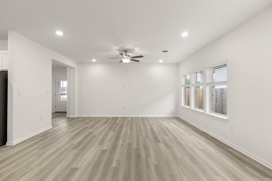 Spacious living area featuring light-colored flooring, recessed lighting, and a ceiling fan