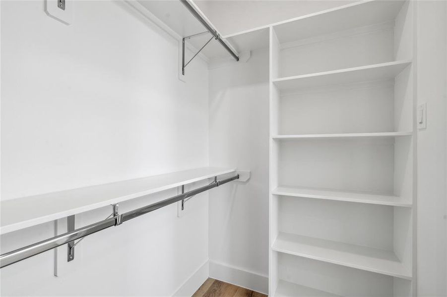 This walk in closet also comes equipped with custom shelves and sleek metal rods to tie the room together.